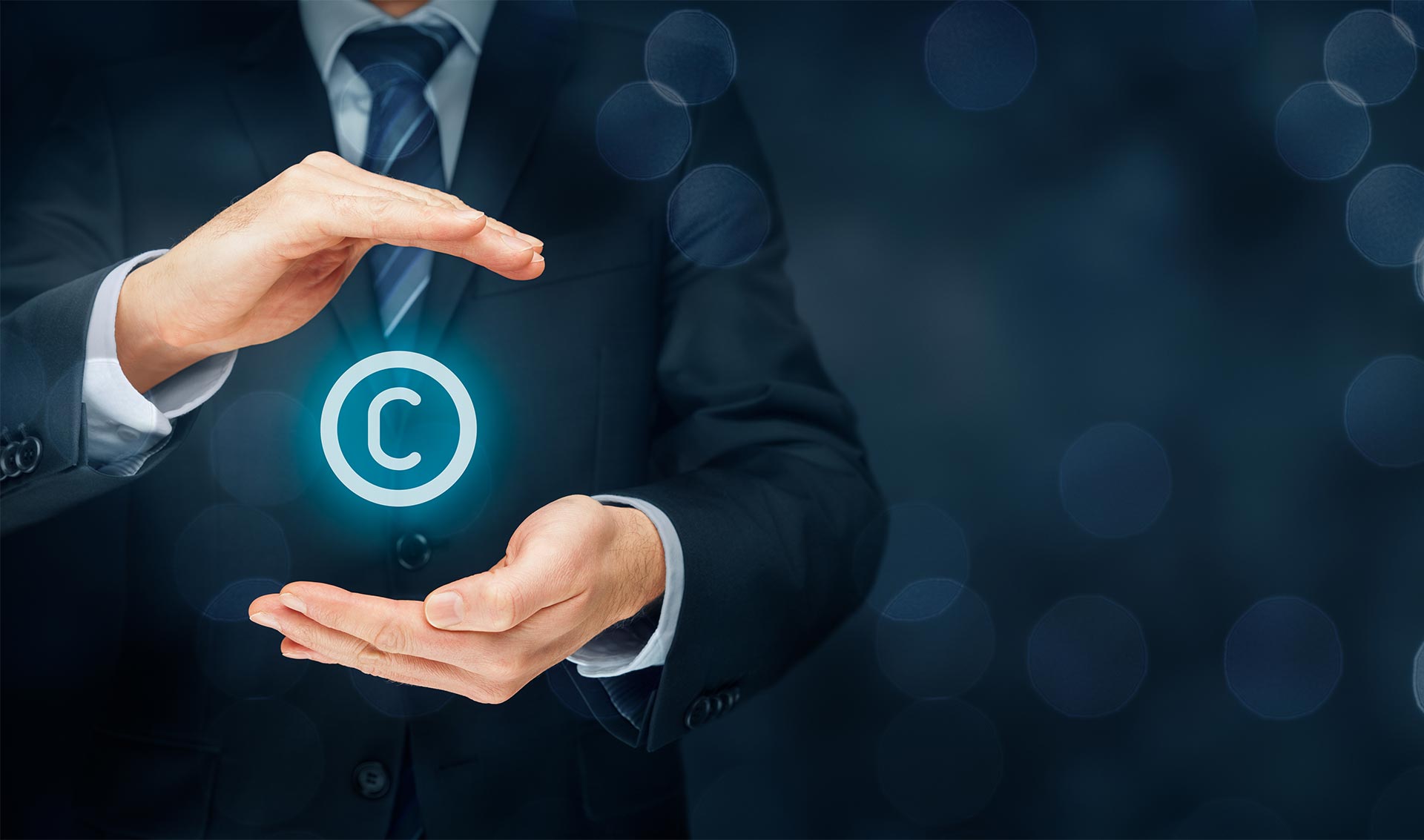 A person in a suit holds their hands around a glowing copyright symbol, representing strong copyright protection, against a dark, blurred background.