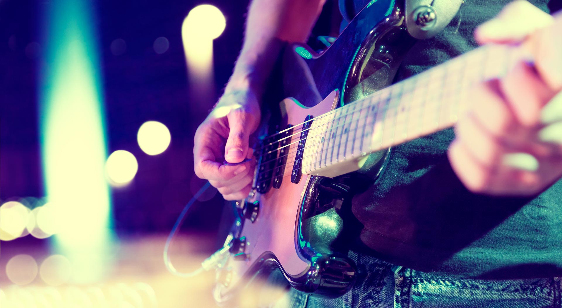 Close-up of a person playing an electric guitar on stage, with blurred lights in the background—much like business & litigation lawyers performing under pressure in the spotlight.