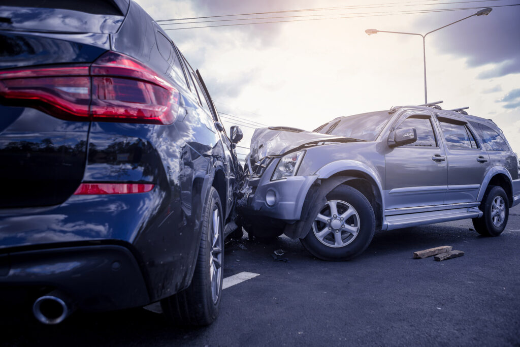 Two SUVs are involved in a head-on collision on a road, with visible damage to both vehicles and debris on the ground—an accident where a NYC personal injury lawyer could help victims seek compensation.