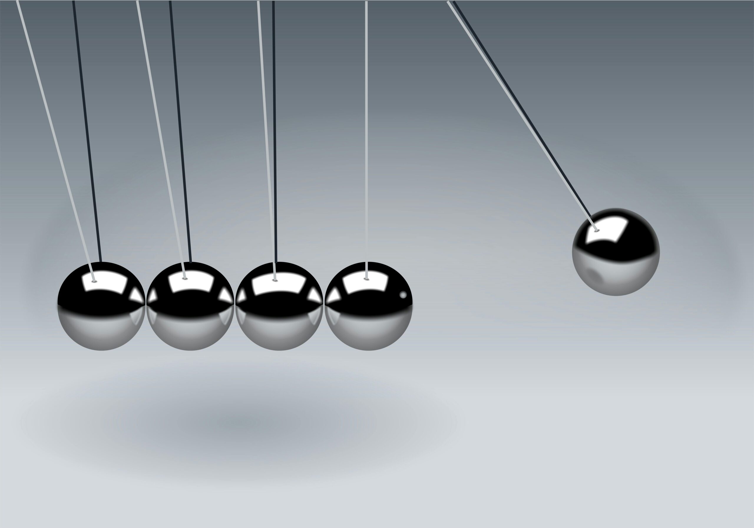 A swinging metal ball striking a row of stationary balls.